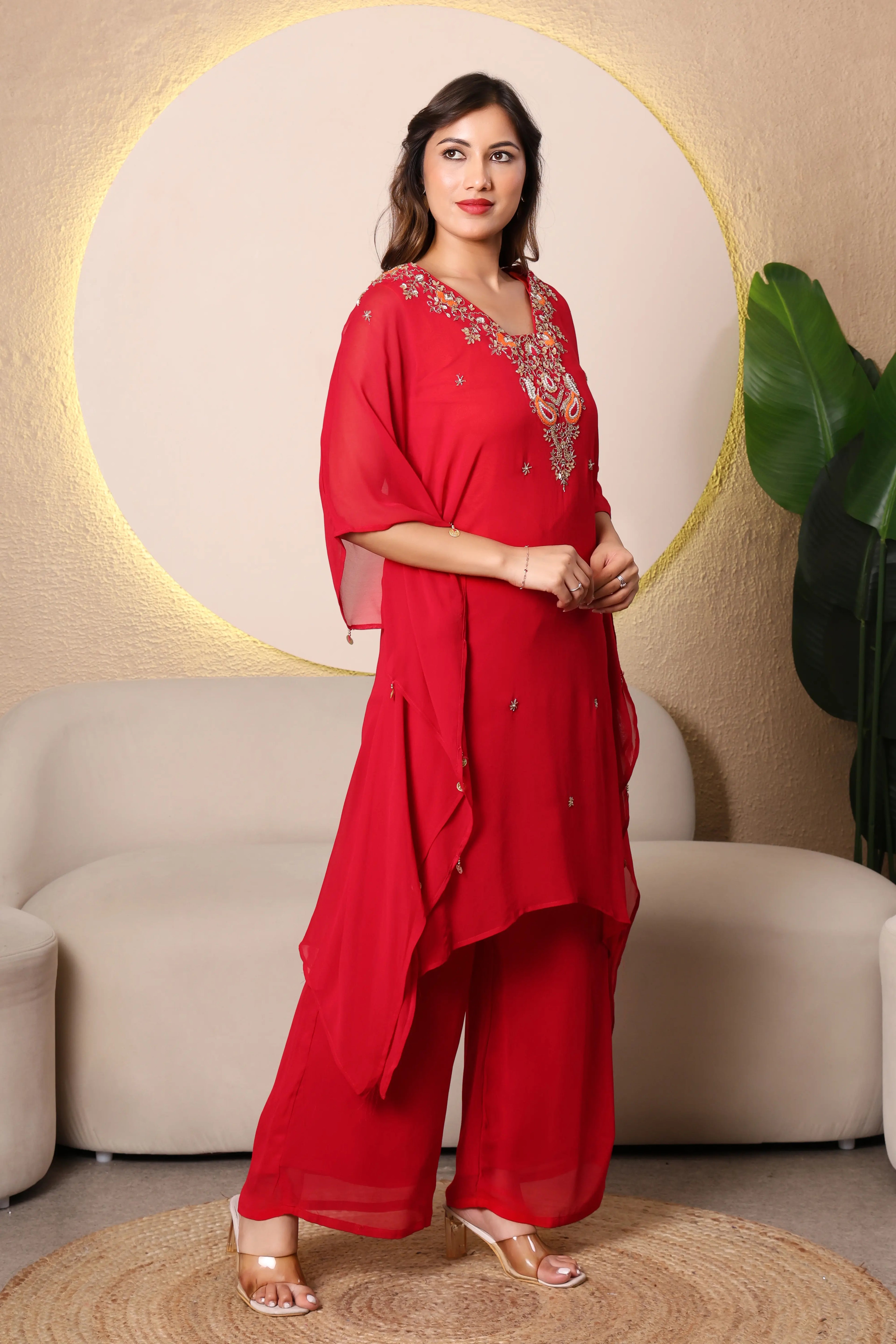 Woman in a red traditional outfit ith intricate cutdana and thread embroidery at the neckline, paired with a shantoon slip and crepe bell bottoms, 