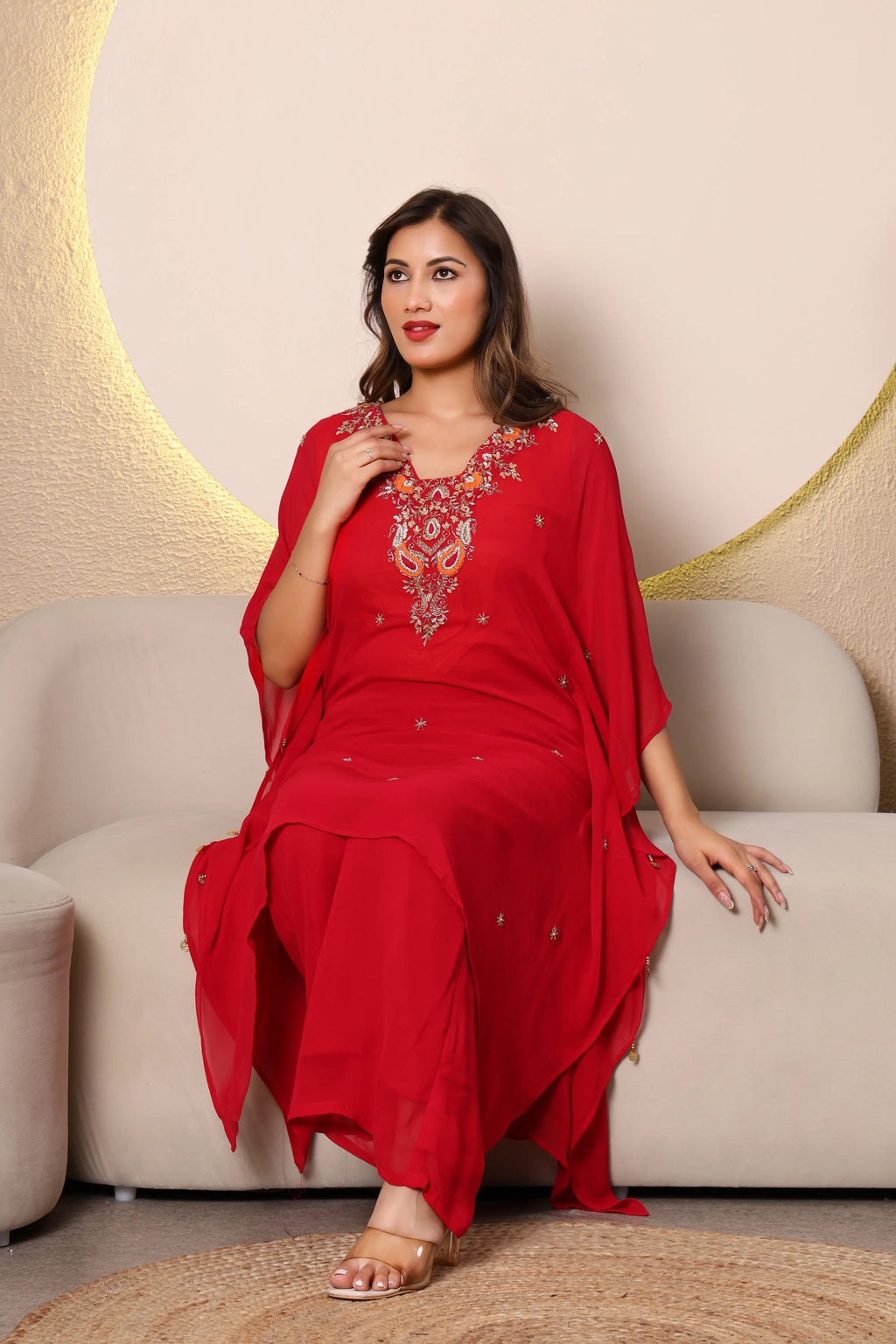 Woman in a red traditional outfit ith intricate cutdana and thread embroidery at the neckline, paired with a shantoon slip and crepe bell bottoms, 