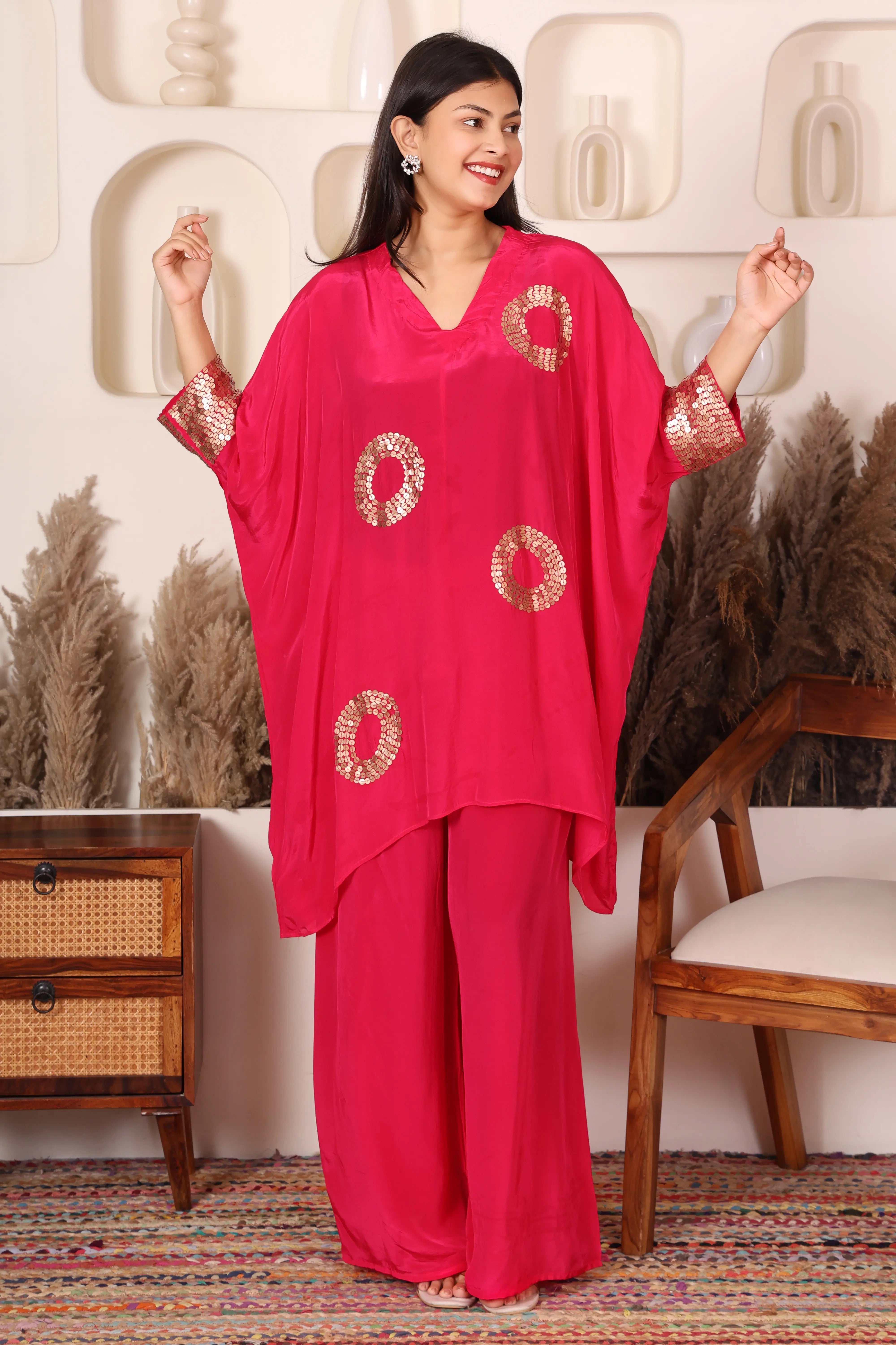 Woman wearing a bright pink outfit with gold patterns.