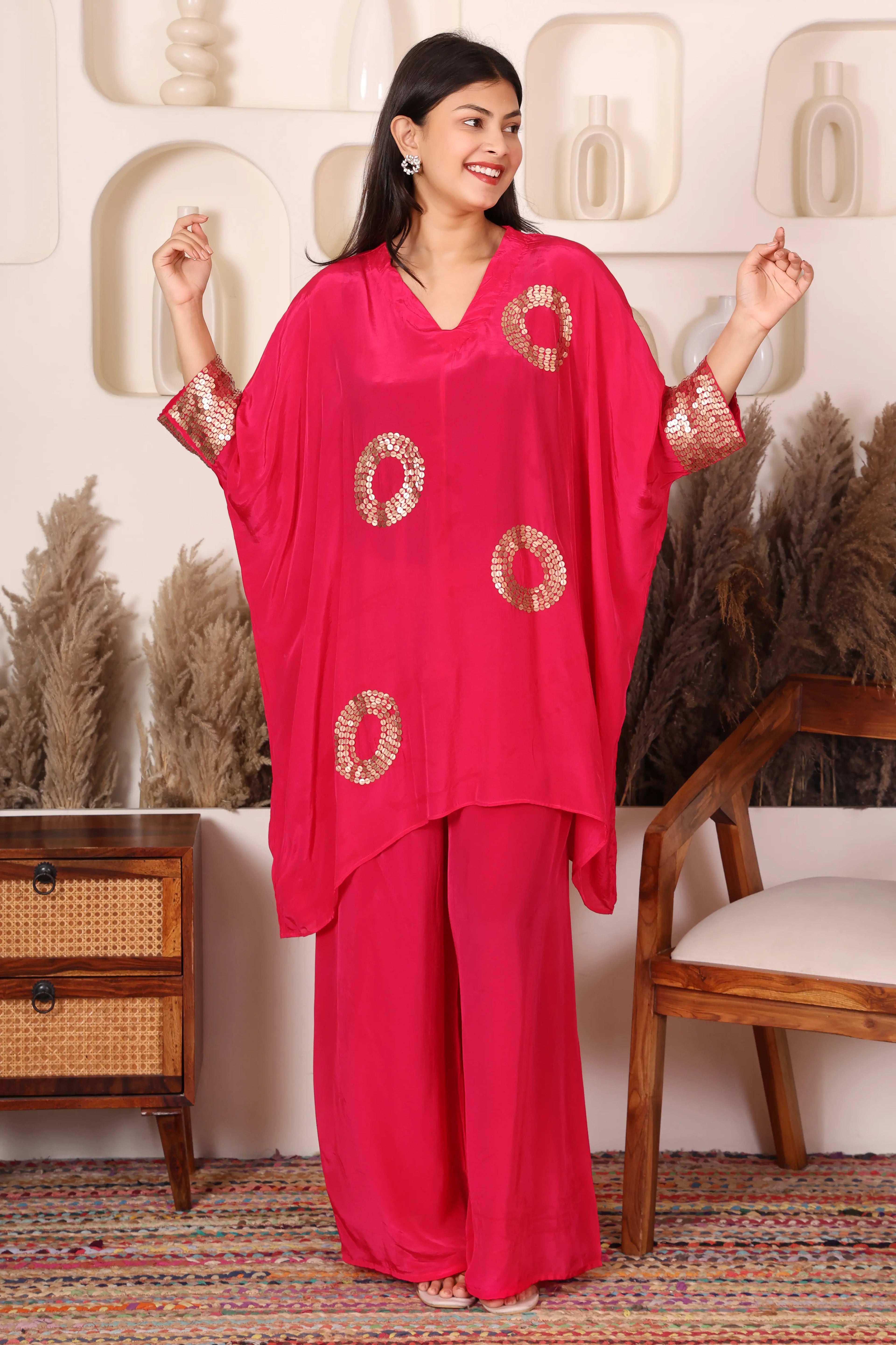 Woman wearing a bright pink outfit with gold patterns.