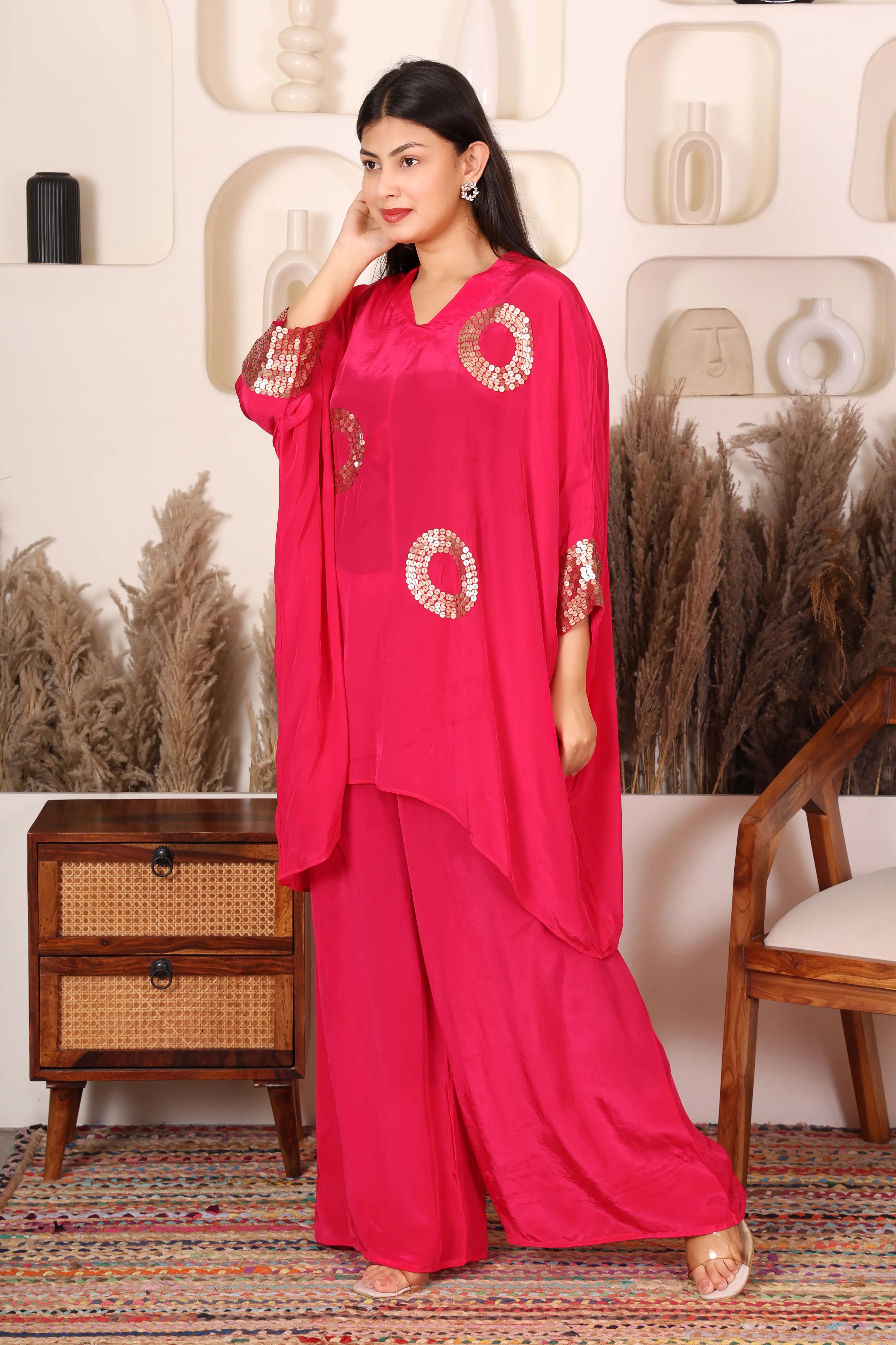 Woman wearing a bright pink outfit with gold patterns.