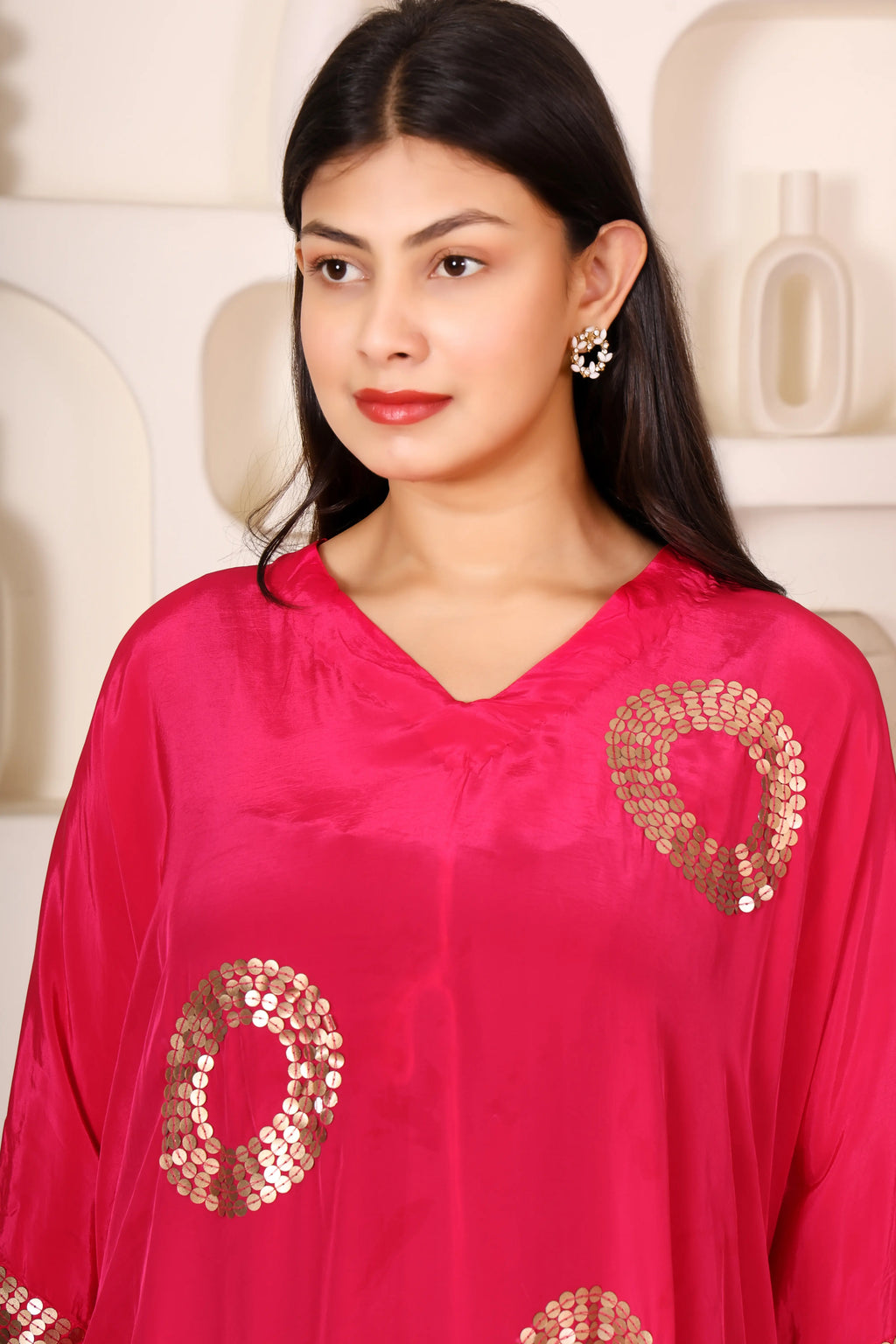 Woman wearing a bright pink outfit with gold patterns.