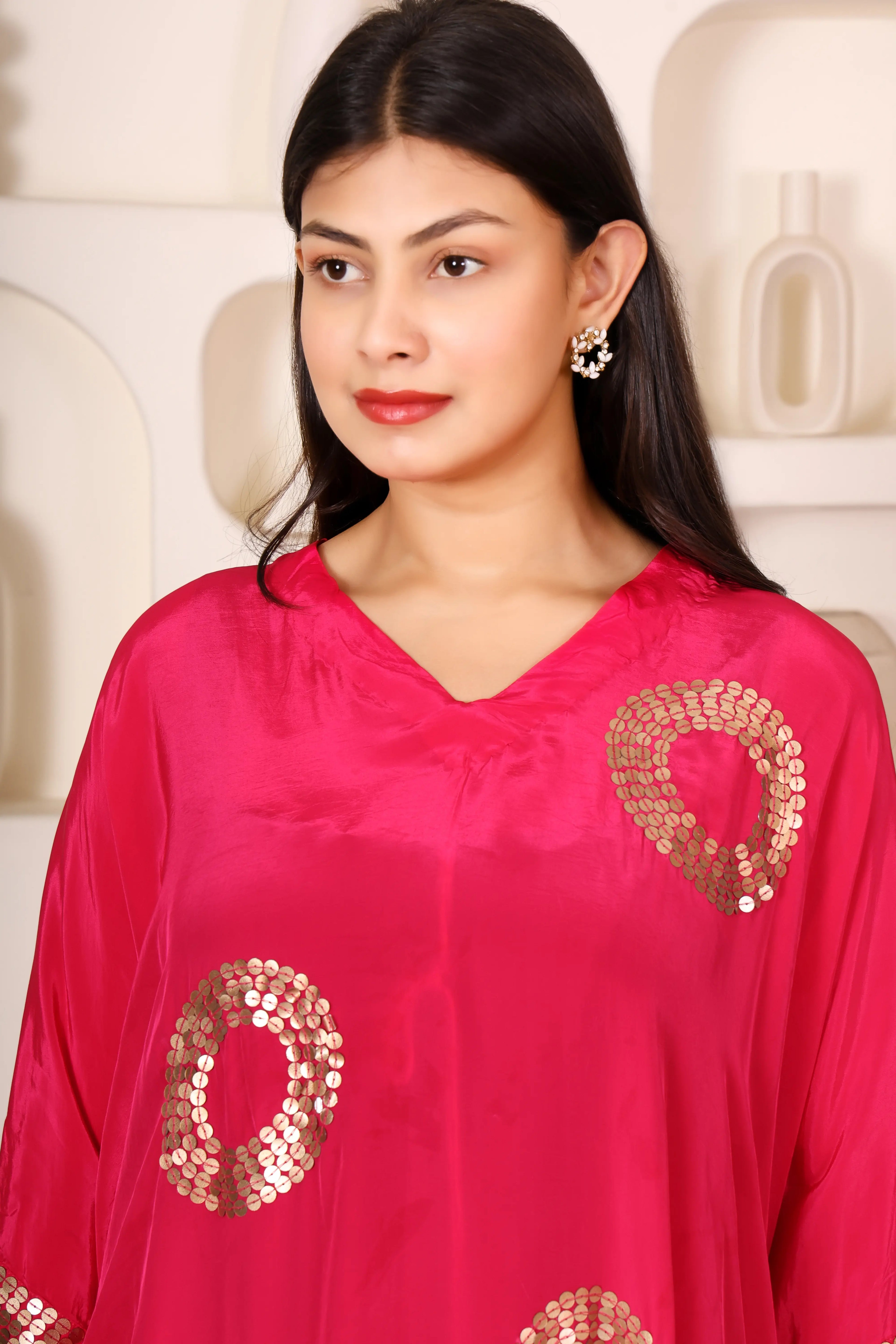 Woman wearing a bright pink outfit with gold patterns.
