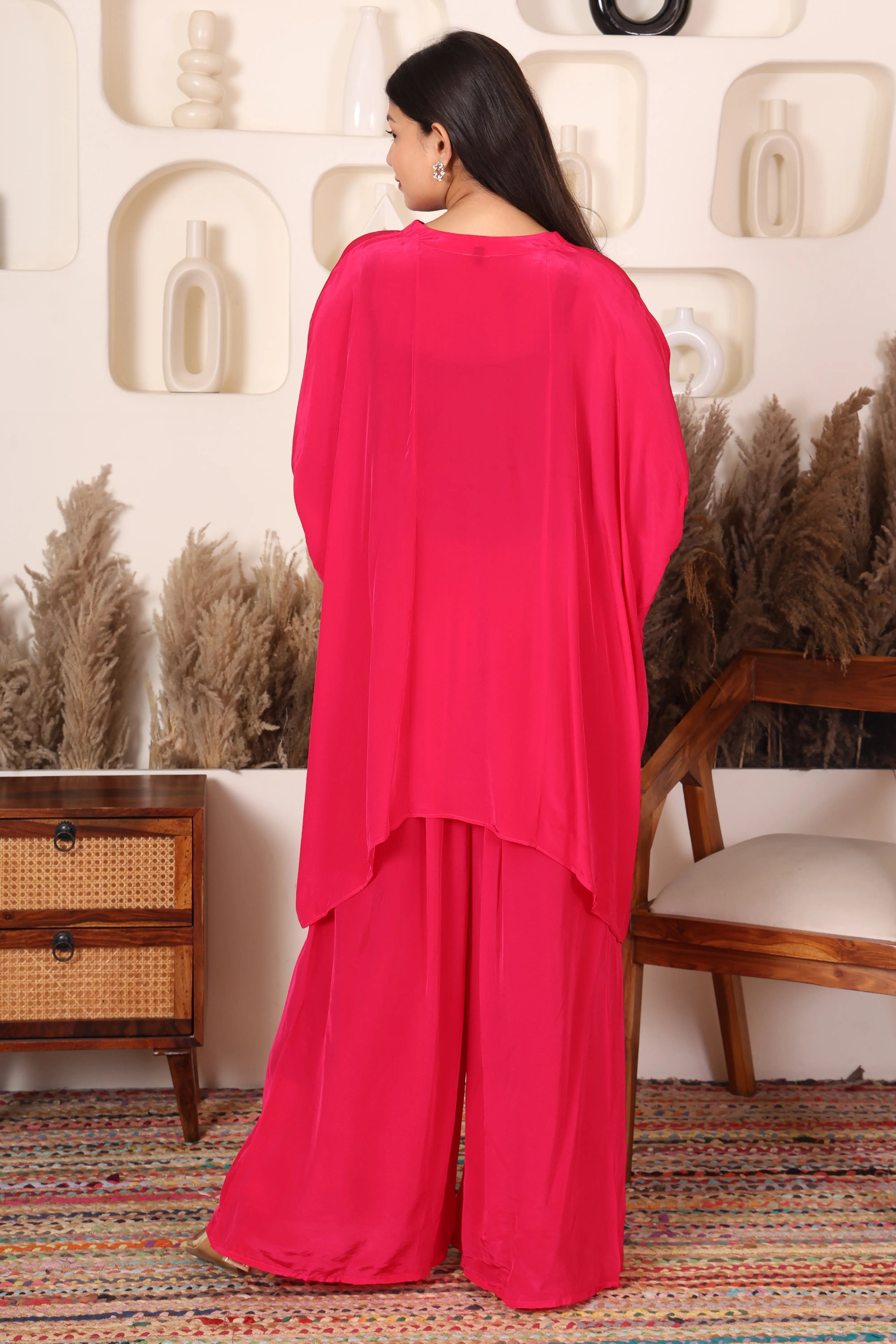 Woman wearing a bright pink outfit with gold patterns.