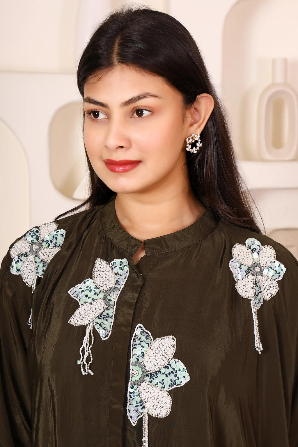 Woman wearing a dark brown traditional outfit with floral embroidery 
