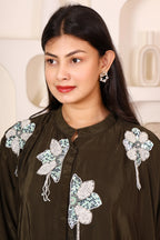 Woman wearing a dark brown traditional outfit with floral embroidery 