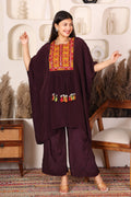 Woman wearing a dark purple traditional outfit with colorful embroidery in a decorative setting.