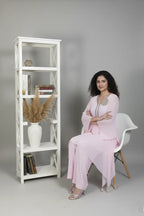 Woman wearing A soft pink pure georgette kurti set featuring fine cutdana and stone work, paired with crepe bell-bottom pants.