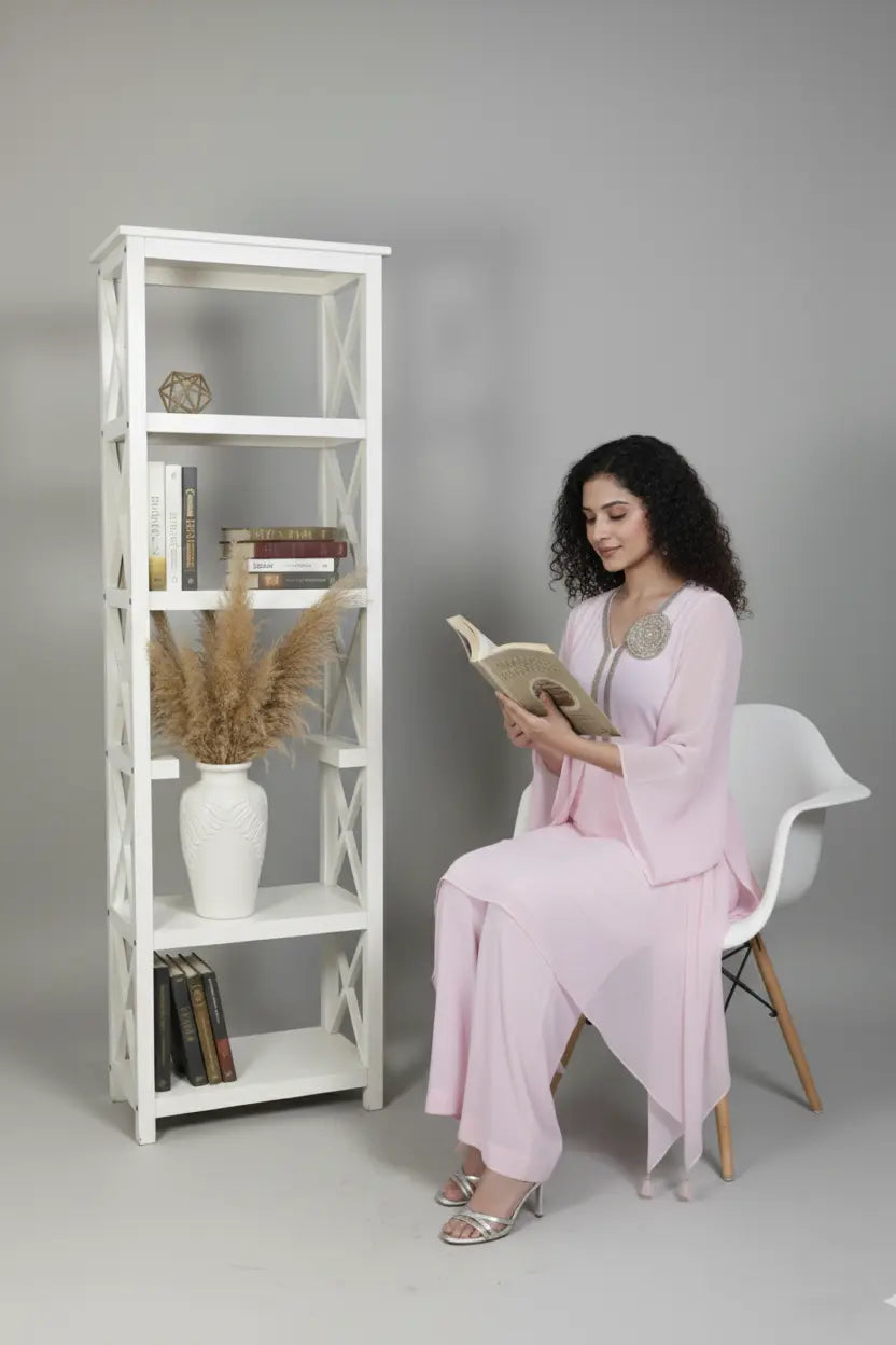 Woman wearing A soft pink pure georgette kurti set featuring fine cutdana and stone work, paired with crepe bell-bottom pants.