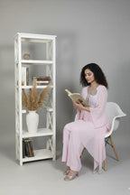 Woman wearing A soft pink pure georgette kurti set featuring fine cutdana and stone work, paired with crepe bell-bottom pants.