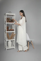 Woman wearing ivory Reagan-style kaftan co-ord set, crafted in pure georgette with vibrant thread floral applique and delicate cutdana accents. Paired with crepe bell-bottom pants and soft shantoon lining for a luxurious festive look.