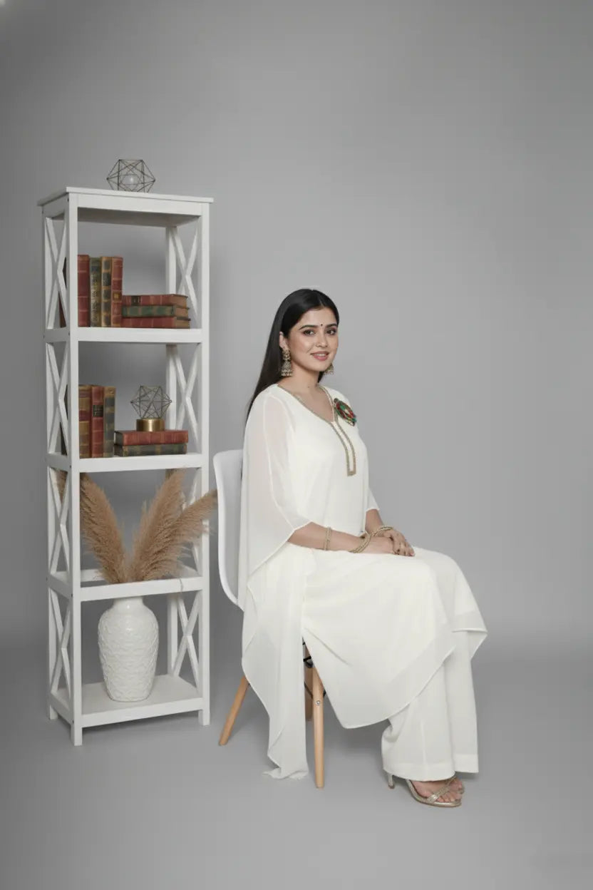 Woman wearing ivory Reagan-style kaftan co-ord set, crafted in pure georgette with vibrant thread floral applique and delicate cutdana accents. Paired with crepe bell-bottom pants and soft shantoon lining for a luxurious festive look.