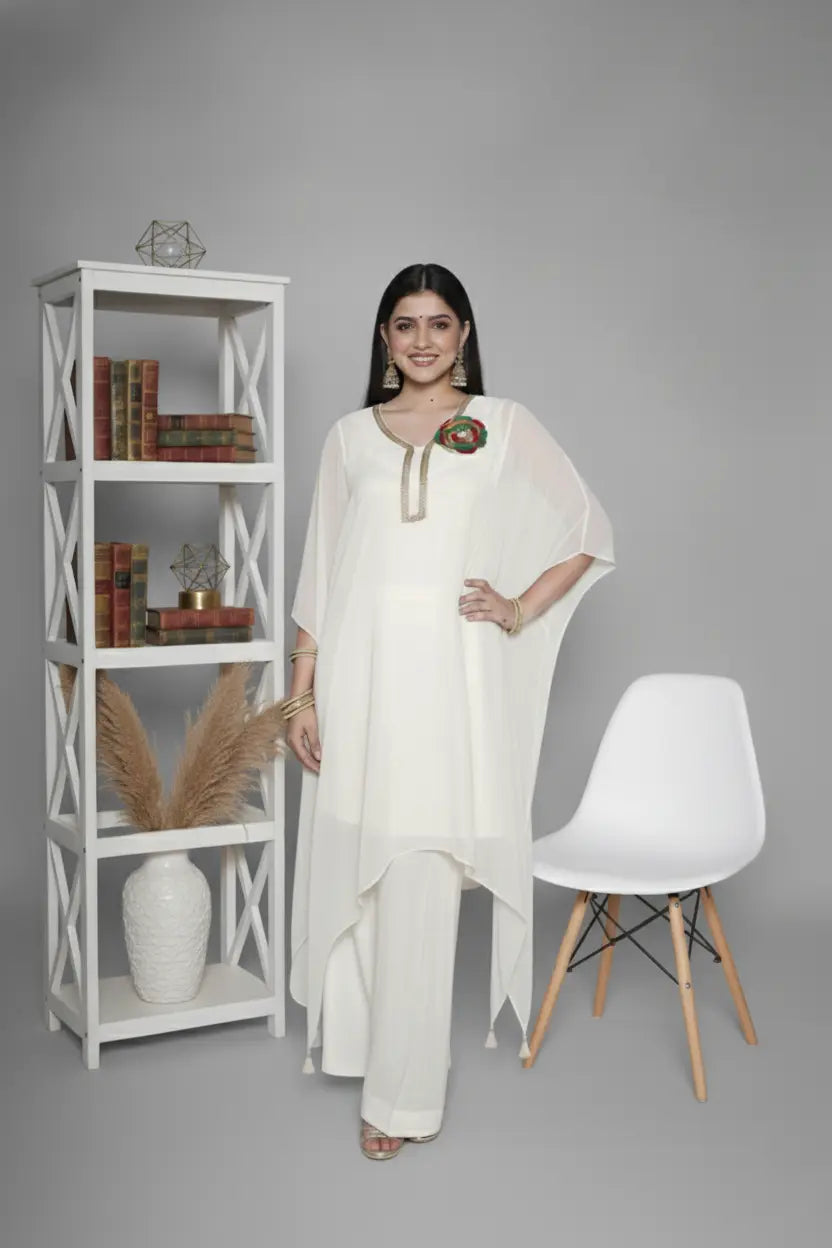 Woman wearing ivory Reagan-style kaftan co-ord set, crafted in pure georgette with vibrant thread floral applique and delicate cutdana accents. Paired with crepe bell-bottom pants and soft shantoon lining for a luxurious festive look.