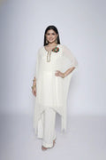 Woman wearing ivory Reagan-style kaftan co-ord set, crafted in pure georgette with vibrant thread floral applique and delicate cutdana accents. Paired with crepe bell-bottom pants and soft shantoon lining for a luxurious festive look.