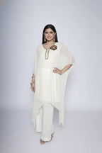 Woman wearing ivory Reagan-style kaftan co-ord set, crafted in pure georgette with vibrant thread floral applique and delicate cutdana accents. Paired with crepe bell-bottom pants and soft shantoon lining for a luxurious festive look.