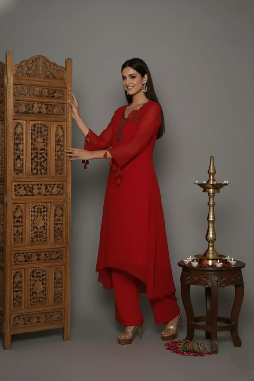 Woman wearing A Bold and elegant crimson georgette kurti set with thread and cutdana work, tassel-detailed sleeves, soft shantoon lining, and stylish crepe bell-bottom pants.