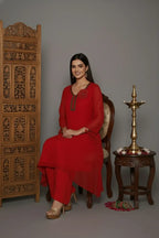 Woman wearing A Bold and elegant crimson georgette kurti set with thread and cutdana work, tassel-detailed sleeves, soft shantoon lining, and stylish crepe bell-bottom pants.
