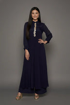 Woman wearing a sophisticated navy blue chinnon chiffon co-ord set featuring a shirt-style kurti with elegant box pleats and hand-crafted zardozi embroidery adorned with pearls and sequins. Paired with soft crepe bell-bottom pants and shantoon lining,