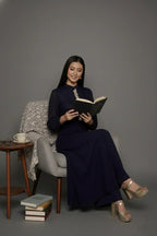 Woman wearing a sophisticated navy blue chinnon chiffon co-ord set featuring a shirt-style kurti with elegant box pleats and hand-crafted zardozi embroidery adorned with pearls and sequins. Paired with soft crepe bell-bottom pants and shantoon lining,