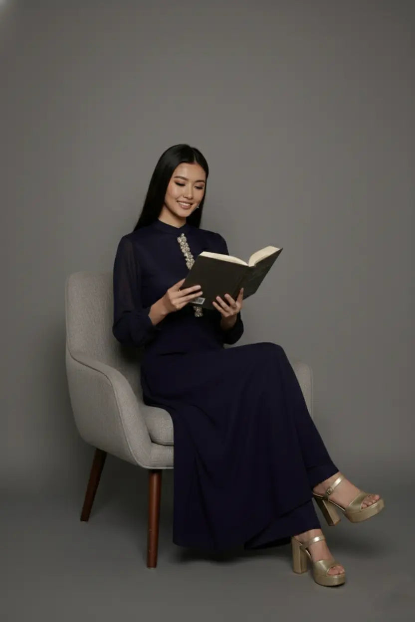 Woman wearing a sophisticated navy blue chinnon chiffon co-ord set featuring a shirt-style kurti with elegant box pleats and hand-crafted zardozi embroidery adorned with pearls and sequins. Paired with soft crepe bell-bottom pants and shantoon lining,