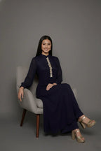 Woman wearing a sophisticated navy blue chinnon chiffon co-ord set featuring a shirt-style kurti with elegant box pleats and hand-crafted zardozi embroidery adorned with pearls and sequins. Paired with soft crepe bell-bottom pants and shantoon lining,